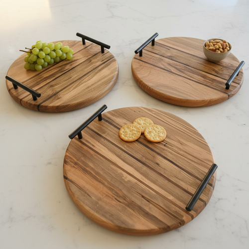 Three round rustic wooden serving trays with black metal handles with minimal food styling on a white marble surface